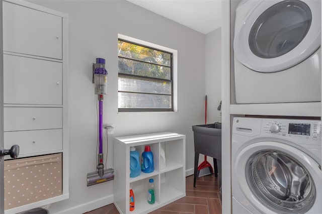 laundry room featuring wood finished floors, stacked washer and clothes dryer, laundry area, and baseboards