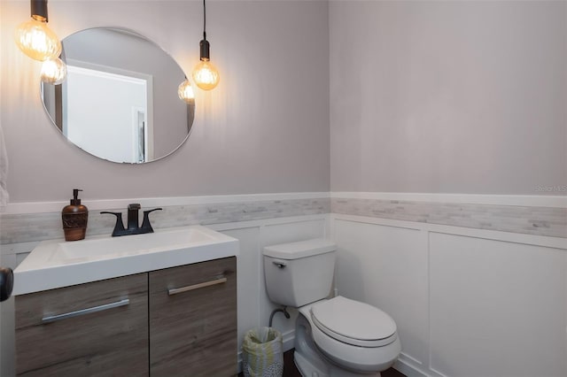 bathroom with vanity, toilet, and wainscoting
