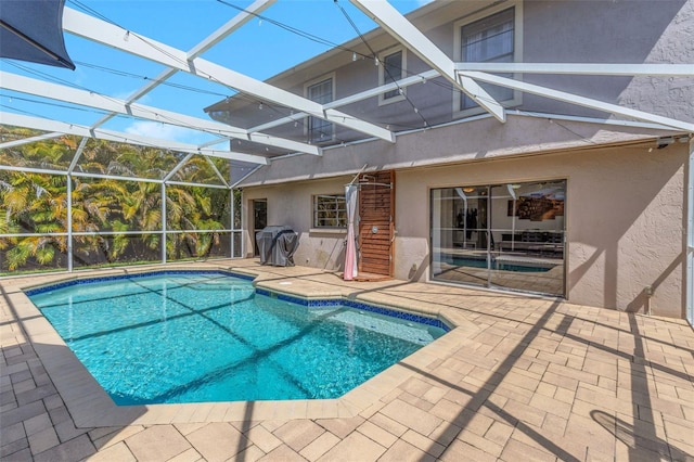 pool featuring glass enclosure and a patio area