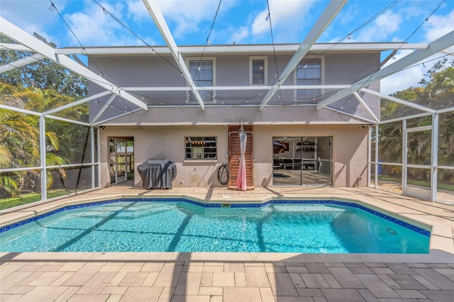 rear view of house featuring a patio, a lanai, stucco siding, and an outdoor pool