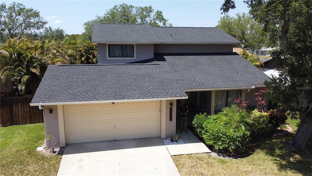 view of front of house with driveway, fence, a shingled roof, stucco siding, and a garage