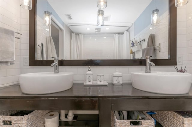 full bathroom featuring double vanity, a sink, tile walls, and visible vents