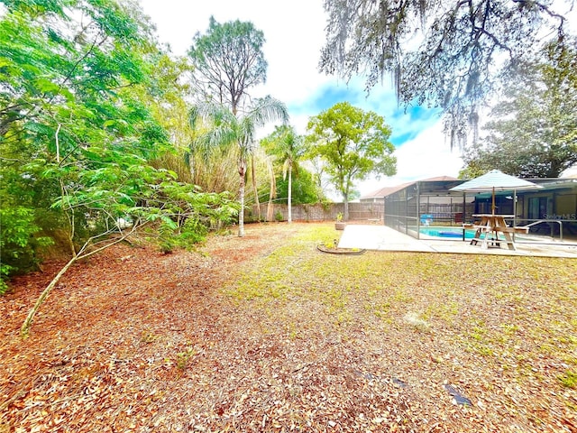 view of yard with fence, a patio area, glass enclosure, and a fenced in pool