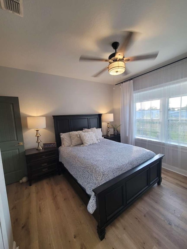 bedroom with light wood-style floors, ceiling fan, and visible vents