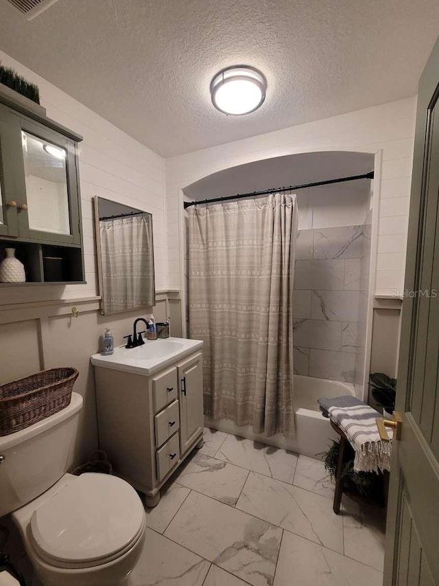 full bath with a textured ceiling, vanity, toilet, marble finish floor, and shower / tub combo with curtain