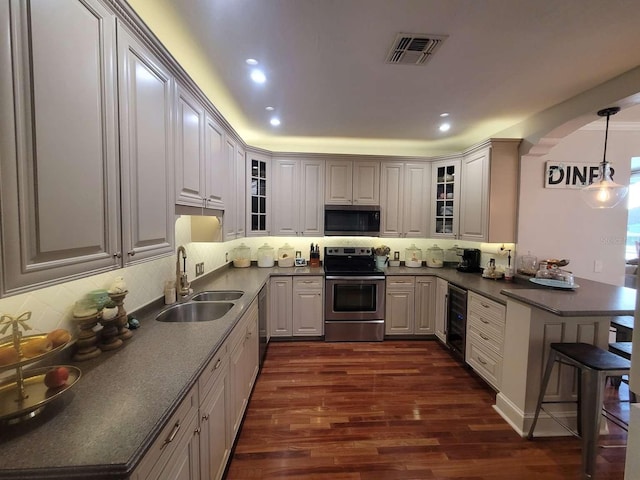 kitchen with appliances with stainless steel finishes, a sink, a peninsula, wine cooler, and visible vents