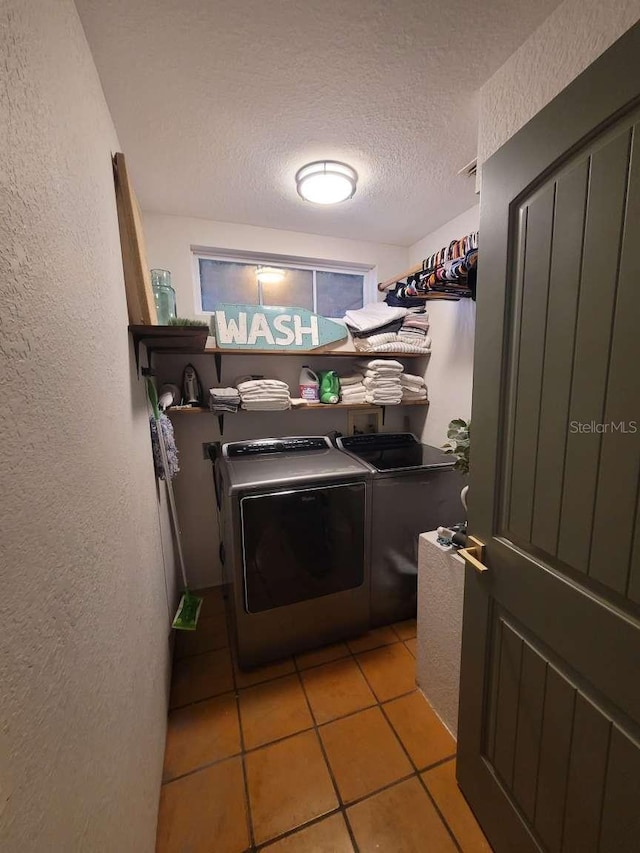 washroom with laundry area, a textured ceiling, a textured wall, and washing machine and clothes dryer