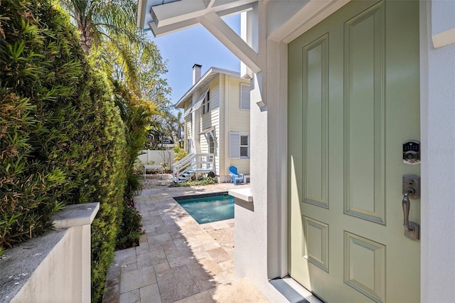 view of exterior entry with an outdoor pool, board and batten siding, and a patio area