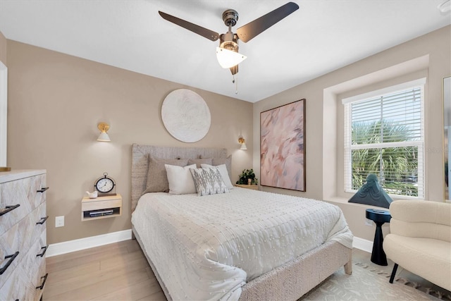 bedroom with ceiling fan, light wood finished floors, and baseboards