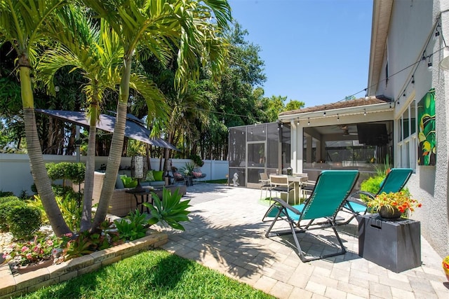 view of patio / terrace with a sunroom, outdoor dining space, ceiling fan, and a fenced backyard