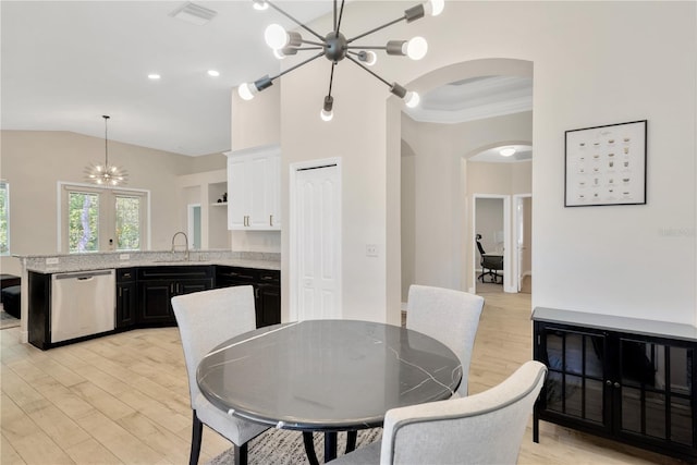 dining room featuring a notable chandelier, light wood-type flooring, visible vents, arched walkways, and lofted ceiling
