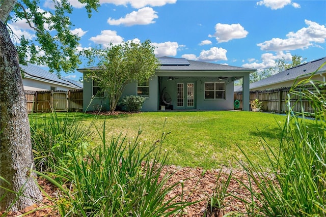back of property featuring a fenced backyard, a ceiling fan, a yard, and stucco siding