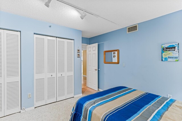 18400 Gulf Blvd Unit 1109, Indian Shores, FL 33785 - carpeted bedroom with multiple closets, baseboards, a ceiling fan, rail lighting, and a textured ceiling