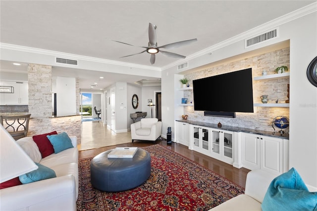 living room with wood finished floors, visible vents, a ceiling fan, and crown molding
