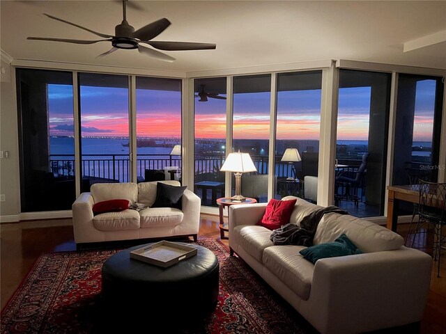 living area with a ceiling fan and a water view