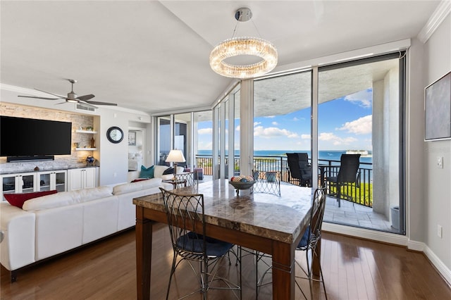 dining room featuring wood finished floors, a water view, floor to ceiling windows, visible vents, and crown molding