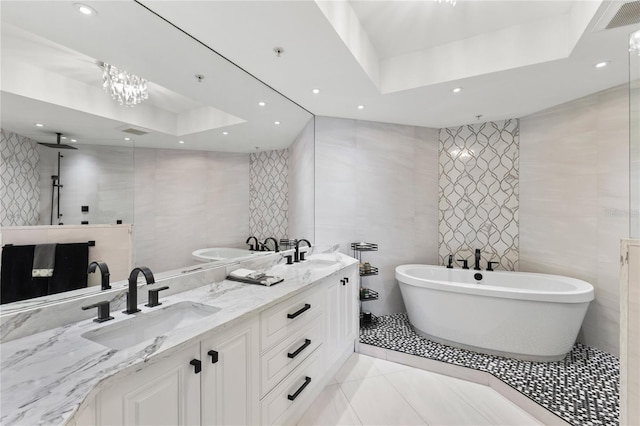 bathroom with tile walls, a tray ceiling, and a sink