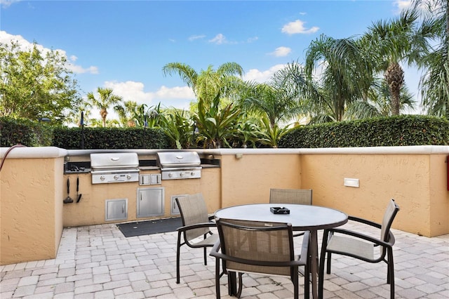view of patio featuring exterior kitchen, outdoor dining area, a grill, and fence