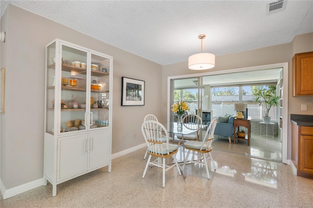 dining space with visible vents, a textured ceiling, and baseboards