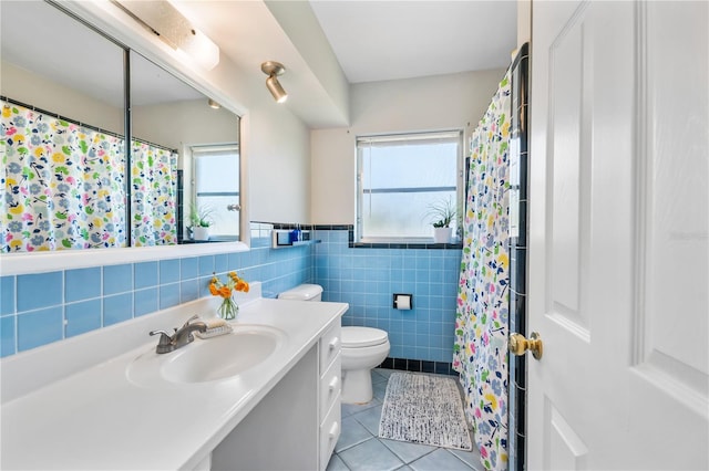 full bath with tile walls, tile patterned floors, a wainscoted wall, vanity, and toilet