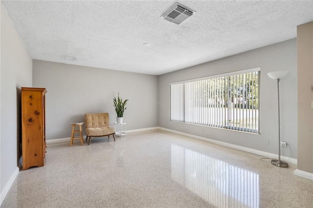 unfurnished room with baseboards, speckled floor, and visible vents