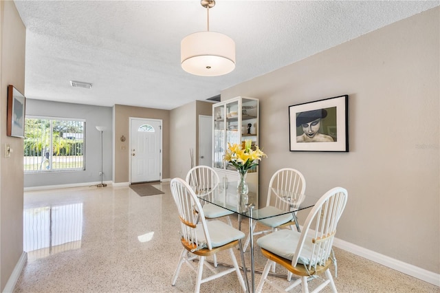 dining area featuring a textured ceiling, baseboards, and speckled floor