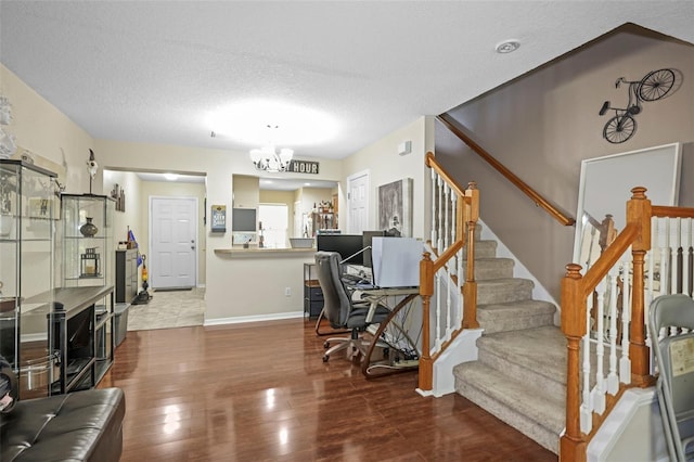 living area with a textured ceiling, wood finished floors, baseboards, a chandelier, and stairs