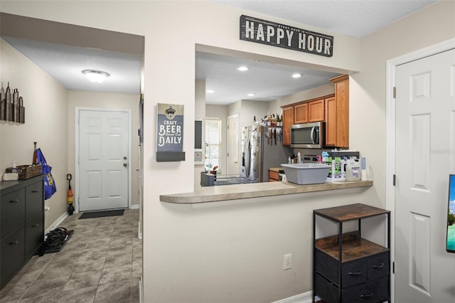 kitchen with brown cabinets, appliances with stainless steel finishes, light countertops, recessed lighting, and baseboards