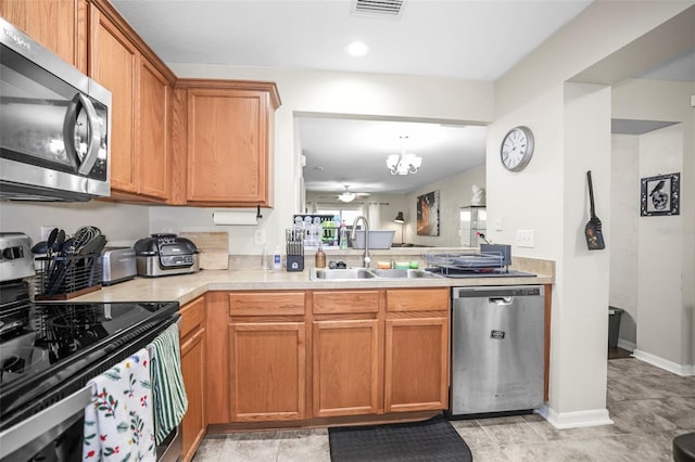 kitchen featuring brown cabinets, appliances with stainless steel finishes, a sink, light countertops, and visible vents