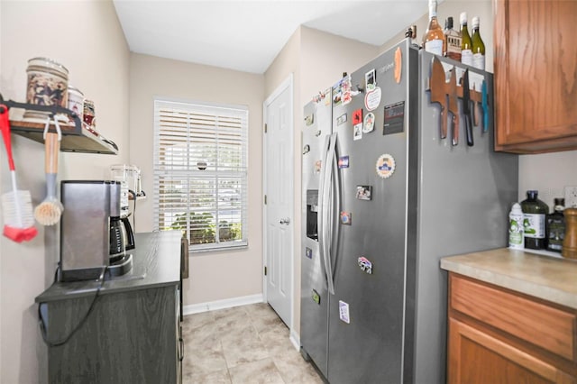 kitchen featuring open shelves, baseboards, light countertops, brown cabinets, and stainless steel fridge with ice dispenser