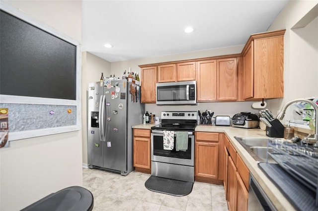 kitchen with light countertops, stainless steel appliances, brown cabinets, and a sink