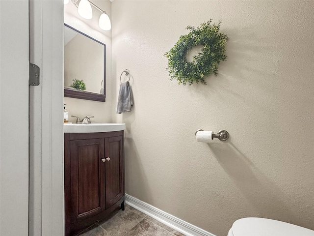 half bath featuring vanity, baseboards, and toilet