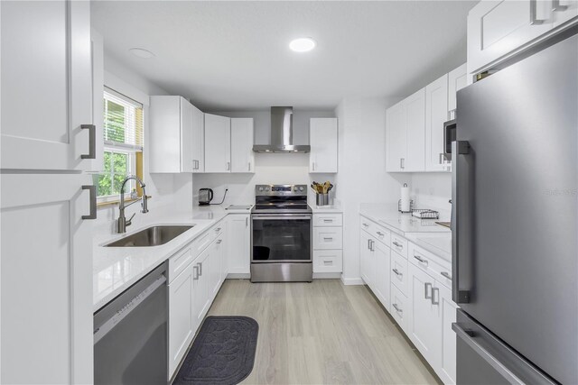 592 Ken Hubbard Rd, Terra Ceia, FL 34250 - kitchen with stainless steel appliances, wall chimney exhaust hood, a sink, light wood-type flooring, and white cabinets