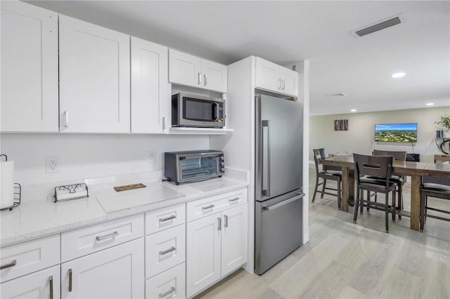 592 Ken Hubbard Rd, Terra Ceia, FL 34250 - kitchen with appliances with stainless steel finishes, white cabinetry, light stone counters, light wood-type flooring, and recessed lighting
