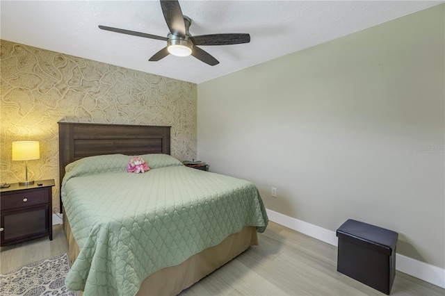 592 Ken Hubbard Rd, Terra Ceia, FL 34250 - bedroom featuring an accent wall, wallpapered walls, light wood finished floors, baseboards, and ceiling fan