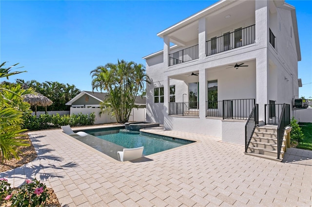 view of pool featuring a patio, fence, a ceiling fan, and a pool with connected hot tub