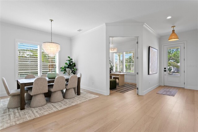 dining space featuring a chandelier, light wood-type flooring, ornamental molding, and baseboards
