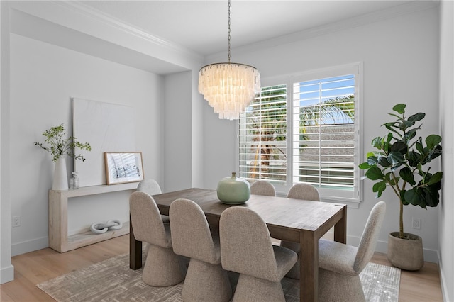 dining area with ornamental molding, light wood-style flooring, a chandelier, and baseboards