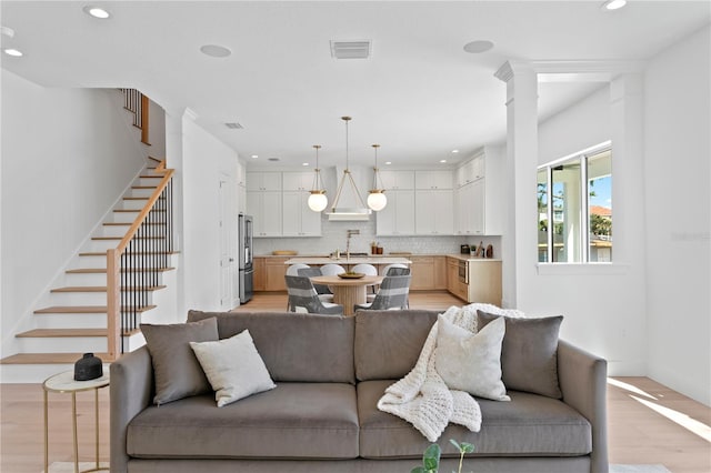 living room featuring visible vents, baseboards, recessed lighting, light wood finished floors, and stairs