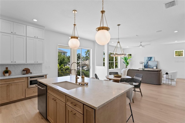 kitchen with light wood finished floors, recessed lighting, a sink, and decorative backsplash