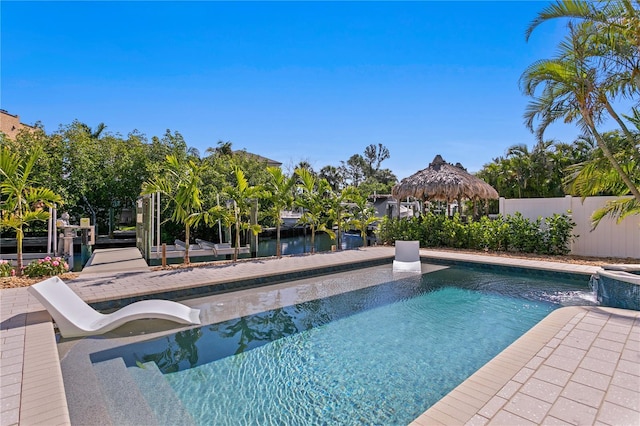 view of pool with fence, a dock, and a pool with connected hot tub