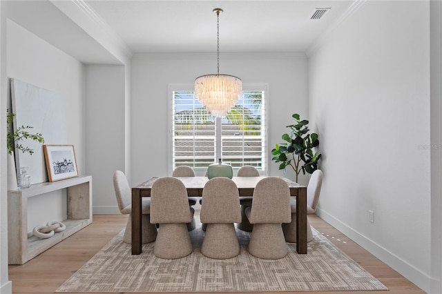 dining room with a chandelier, visible vents, ornamental molding, and light wood-type flooring