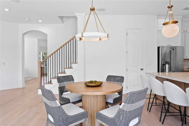 dining area with recessed lighting, arched walkways, light wood-style floors, baseboards, and stairway