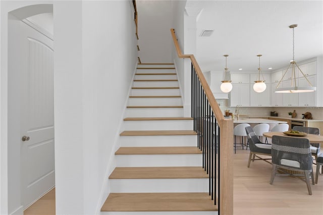 staircase with recessed lighting, arched walkways, visible vents, and wood finished floors