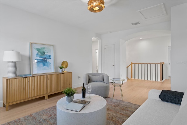 living area with arched walkways, visible vents, and wood finished floors