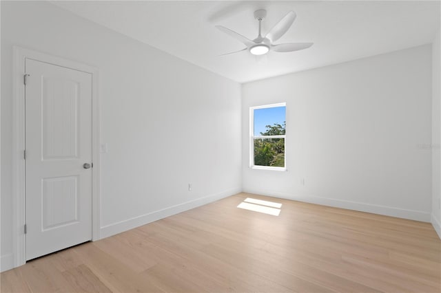 empty room with baseboards, ceiling fan, and light wood-style flooring