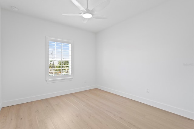 spare room featuring light wood-type flooring, a ceiling fan, and baseboards