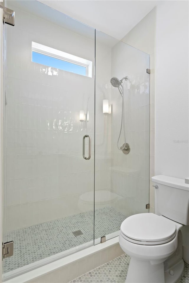 bathroom with toilet, a stall shower, and tile patterned flooring