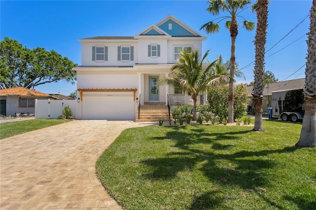 view of front of property featuring decorative driveway, covered porch, a front yard, stucco siding, and a garage