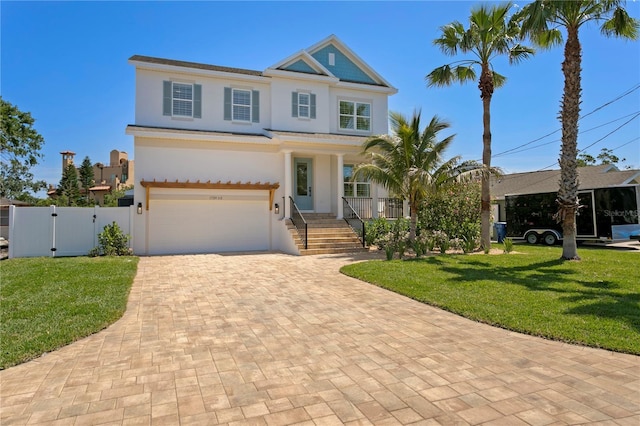 view of front of property with a front yard, a garage, a gate, decorative driveway, and stucco siding